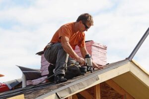 A homeowner checks roof shingles and clear gutters beside a house in early autumn.